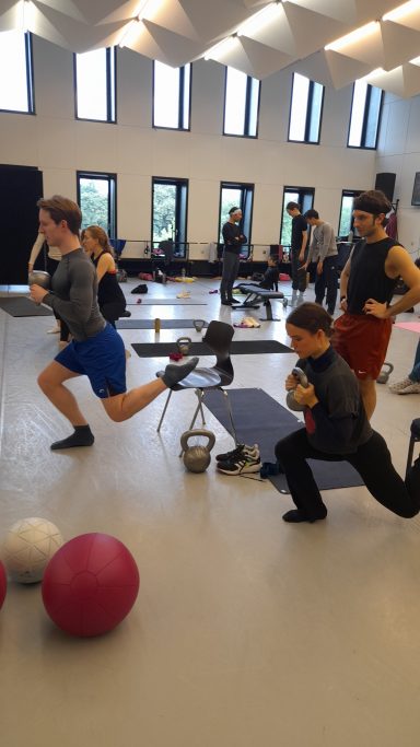 Personen trainieren in einem Fitnessraum mit verschiedenen Geräten und Trainingsbällen.
