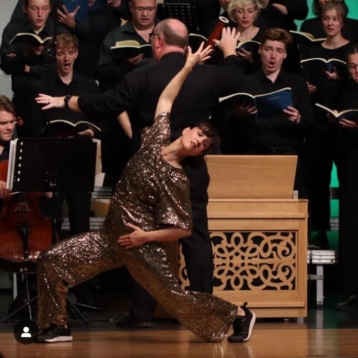 Marlen Schumann tanzt in glänzendem Outfit, umgeben von einem Chor.